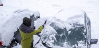 Schneechaos in Norddeutschland: Rechte, Pflichten und praktische Tipps Eine Person entfernt Schnee von der Frontscheibe eines Autos
