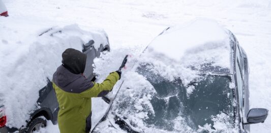 Schneechaos in Norddeutschland: Rechte, Pflichten und praktische Tipps Eine Person entfernt Schnee von der Frontscheibe eines Autos