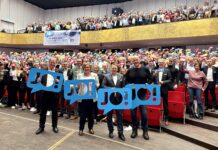Wir sagen „JO!“ zu den Olympischen Spielen in Kiel Viele Menschen stehen im Konzertsaal des Kieler Schlosses und halten bunte Schilder hoch, auf denen "JO!" steht.