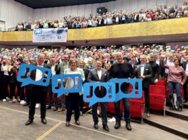 Wir sagen „JO!“ zu den Olympischen Spielen in Kiel Viele Menschen stehen im Konzertsaal des Kieler Schlosses und halten bunte Schilder hoch, auf denen "JO!" steht.