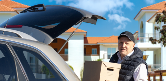 Haushaltsauflösung stressfrei und günstig organisieren Ein älterer Mann mit Basecap verlädt Umzugskartons in den Kofferraum seines Autos