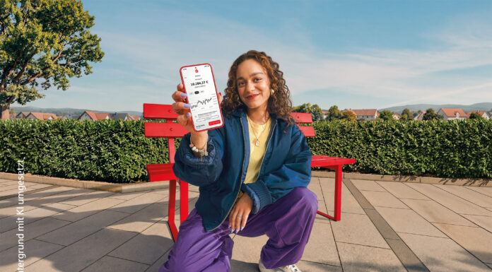 S-Neo – einfach investieren in der App Sparkasse Junge Frau sitzt vor blauem Himmel auf einer roten Bank und hält ein Handy mit Depot-Ansicht nach vorn