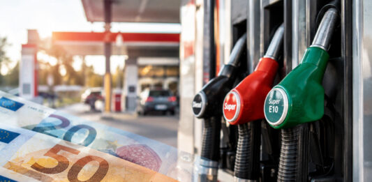 Tankrabatt: Was hohe Spritpreise jetzt für Verbraucher:innen bedeuten Zapfsäulen an einer Tankstelle, im Vordergrund sind transparente Euroscheine zu sehen. KI generiertes Bild.